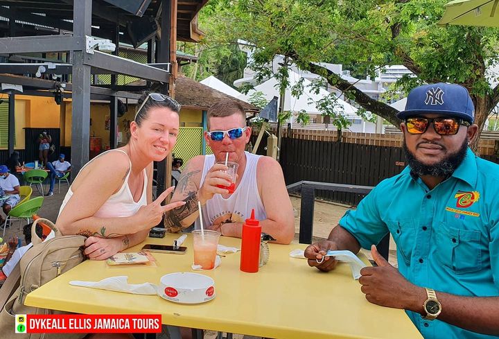 Guests and their driver sitting with drinks at an outdoor table under cover
