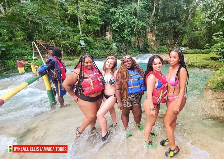 A group of guests in life jackets standing in the turquoise river water at Blue Hole near Ocho Rios