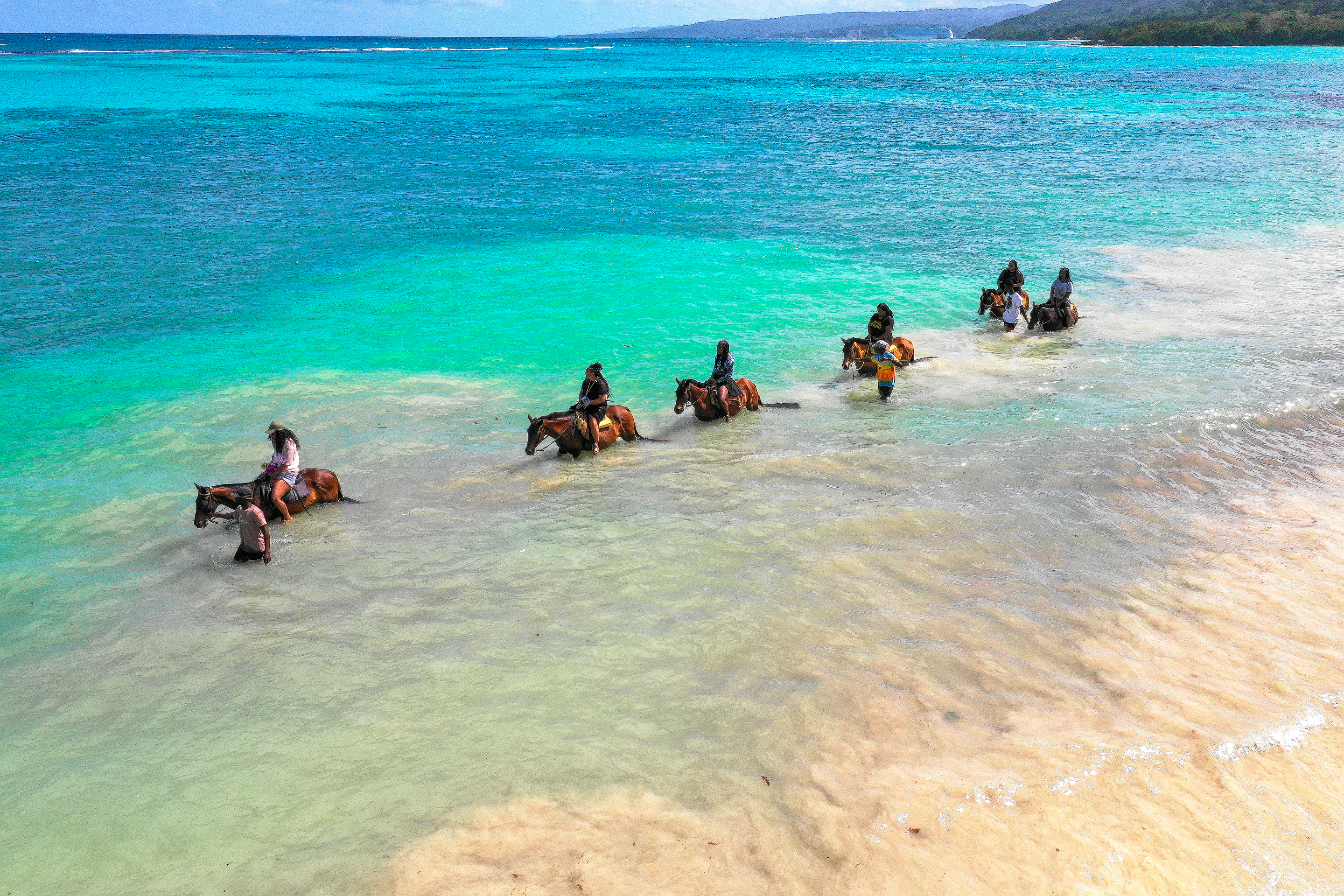 Riders taking horses into the shallows on a Jamaican beach